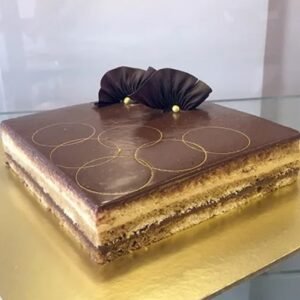 Velvet Gold Opera Cake with layers of rich chocolate, coffee cream, and a glossy finish, elegantly presented on a decorative plate.