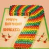 Candyland-themed Number Seven Cake decorated with colorful candies, lollipops, and frosting swirls for a fun birthday celebration.