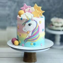 Unicorn-themed cake with golden horn, star decorations, and pastel colors, designed for birthday celebrations.