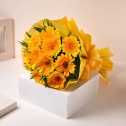 A bouquet of vibrant yellow gerberas with lush green accents, radiating warmth and happiness.